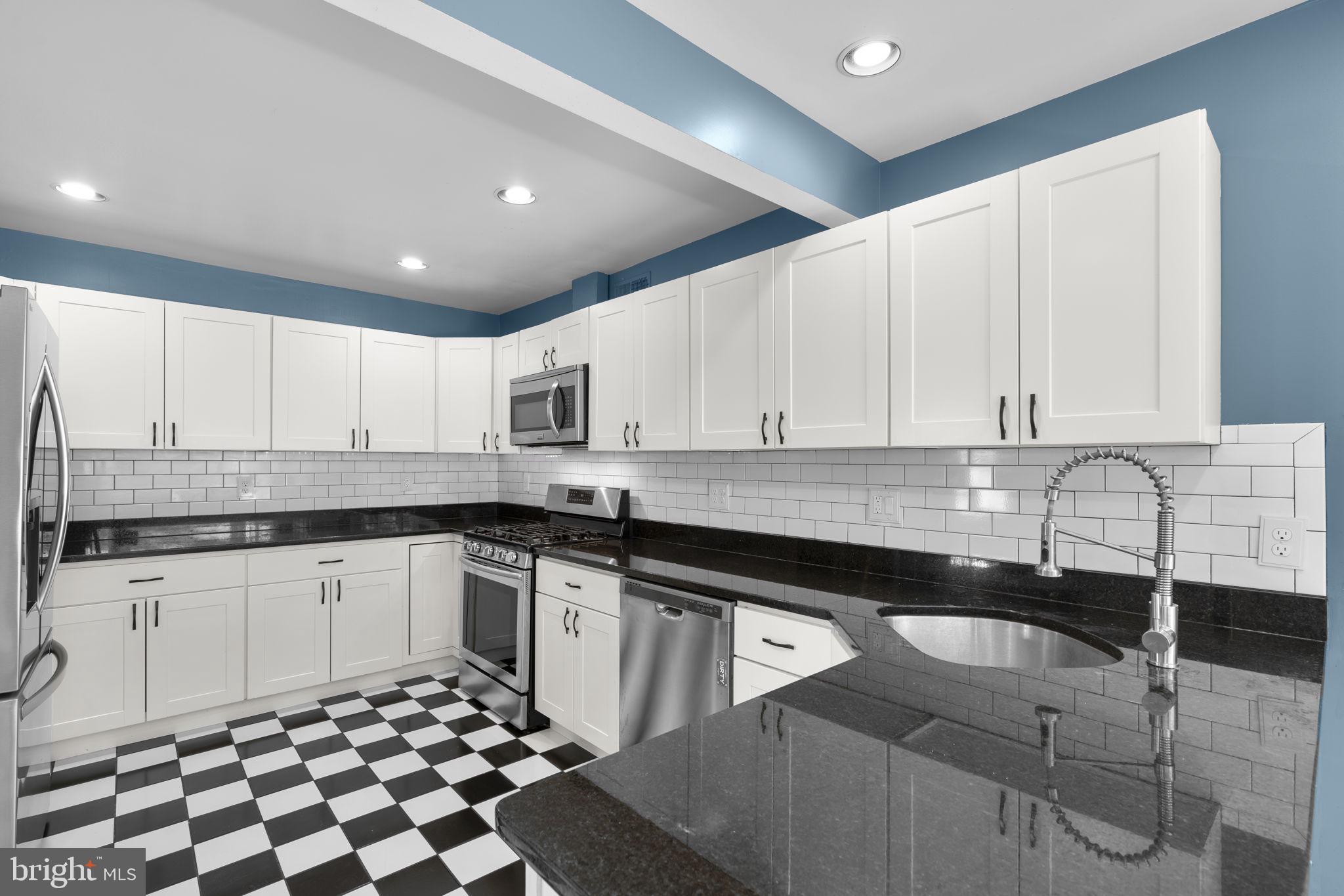 822 Loxford Terrace Silver Spring, MD 20901 - Photo 18 of 61 a kitchen with granite countertop a sink a stove a microwave and cabinets