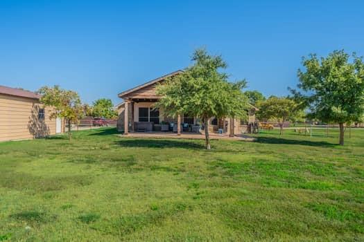 166 Oxford Ranch Road Waxahachie, TX 75167 - Photo 24 of 27 Expansive grassy yard with mature trees, a covered patio, and an outbuilding