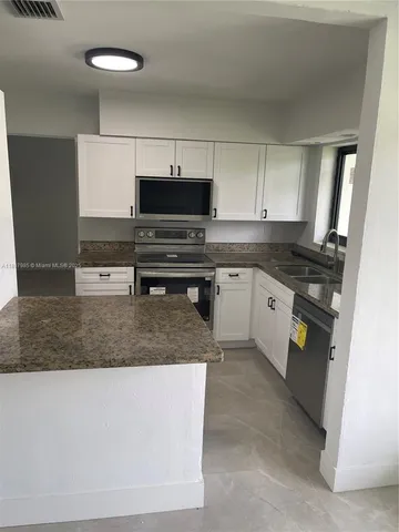 a kitchen with stainless steel appliances granite countertop a stove a sink and a microwave