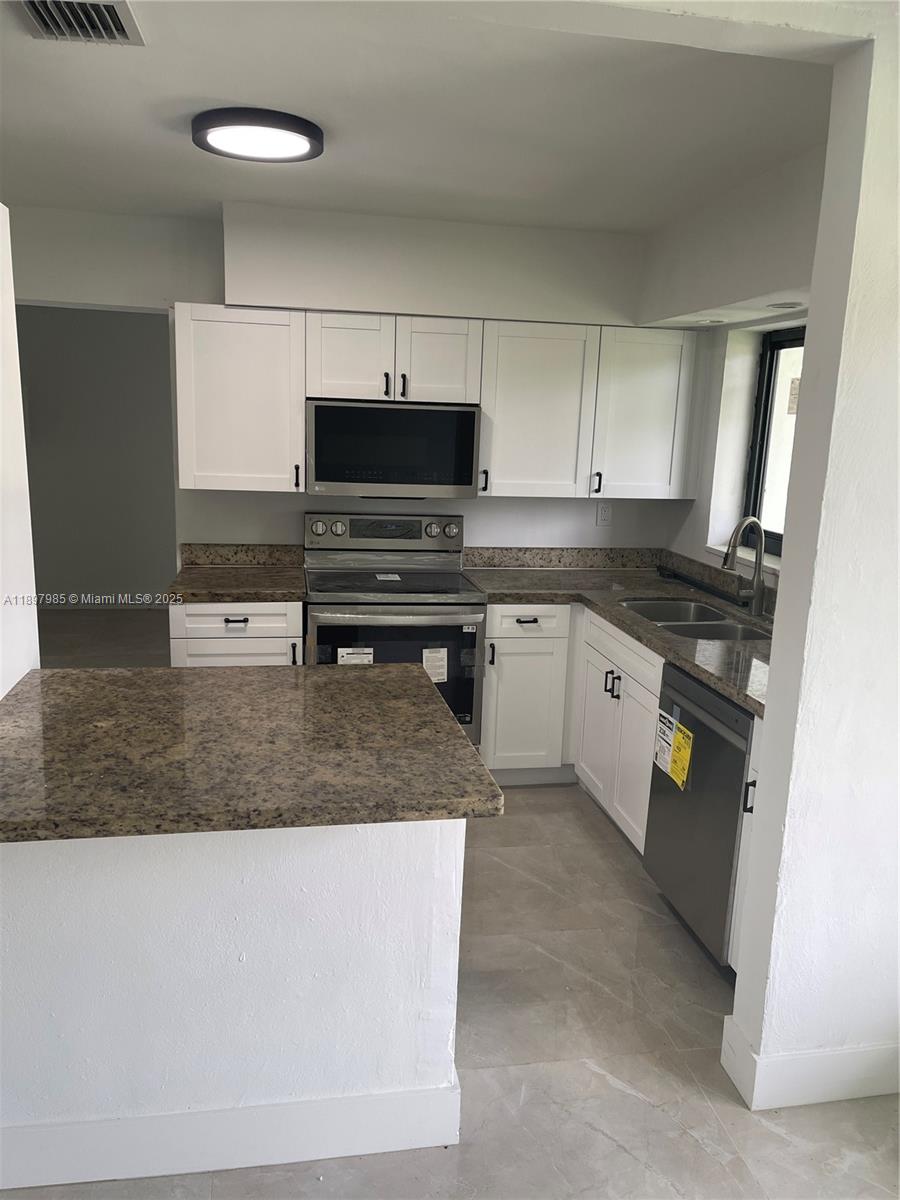 4310 Northwest 182nd Street Miami Gardens, FL 33055 - Photo 3 of 12 a kitchen with stainless steel appliances granite countertop a stove a sink and a microwave