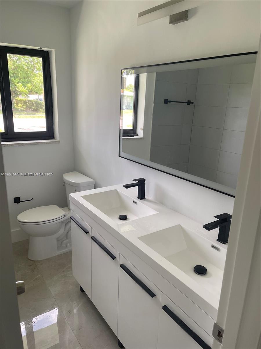 4310 Northwest 182nd Street Miami Gardens, FL 33055 - Photo 6 of 12 a bathroom with a sink a toilet and mirror