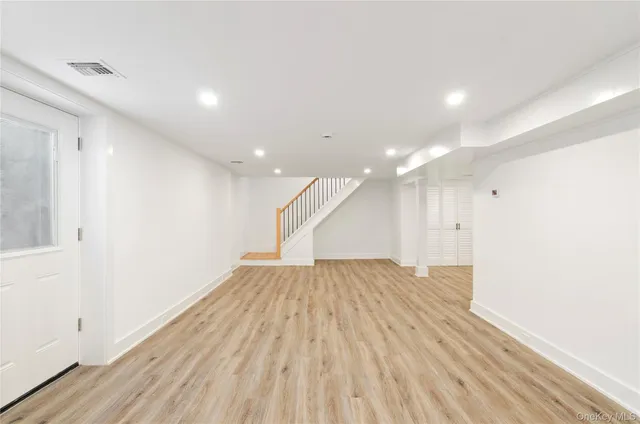 an empty room with wooden floor and entrance to ceiling window