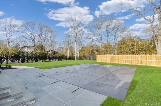 a view of a white house next to a yard with big trees