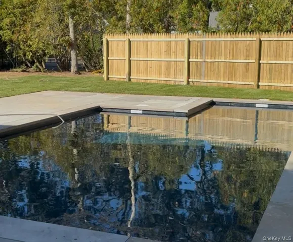 a view of a white house in a big yard with palm trees
