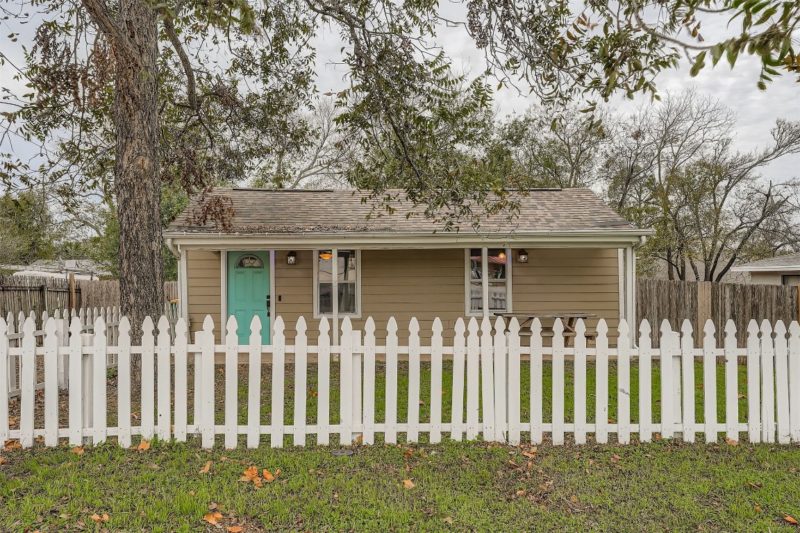 View of front facade with a fenced front yard and roof with shingles