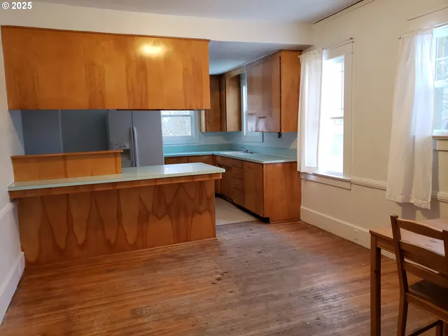 an empty room with wooden floor a fireplace and windows