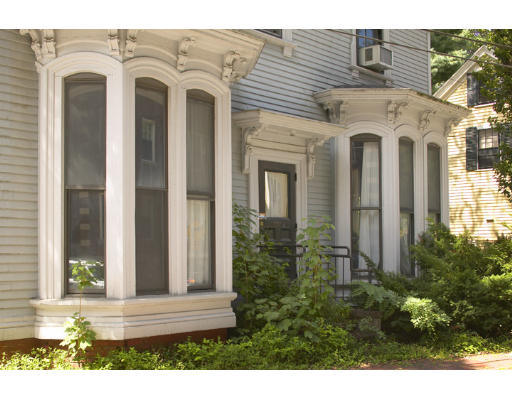 a view of a white house with large windows and a small yard