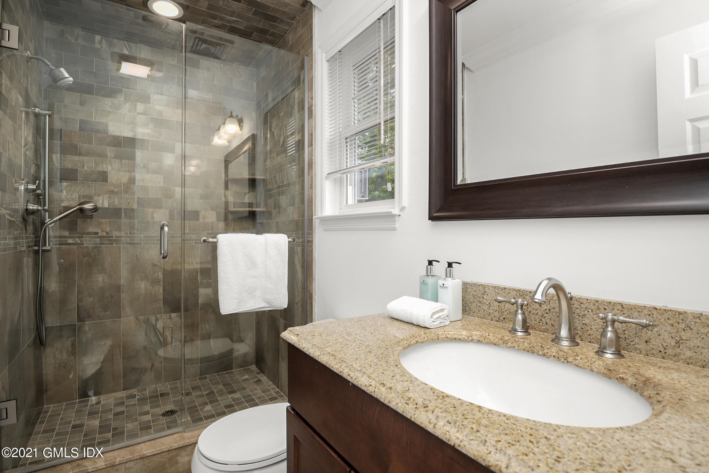 100 Strickland Road, Unit 1 Cos Cob, CT 06807 - Photo 12 of 29 a bathroom with a granite countertop sink a toilet a mirror and shower
