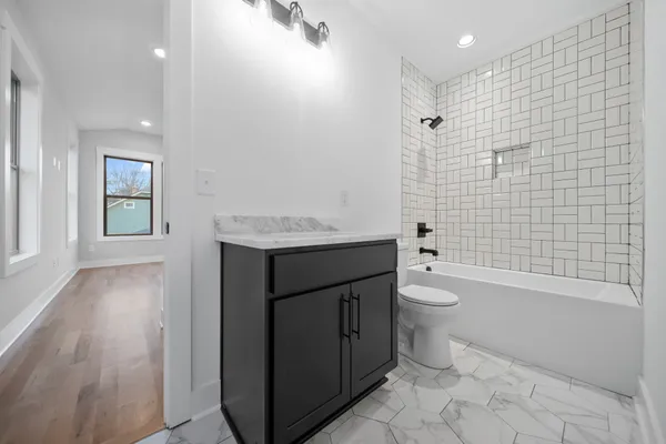 a bathroom with a granite countertop toilet a sink a mirror and shower