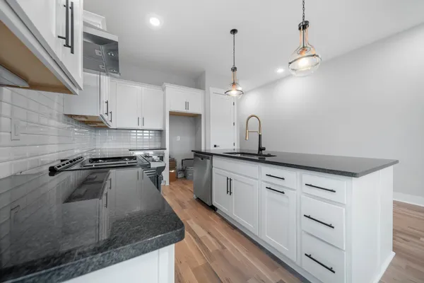 a kitchen with stainless steel appliances granite countertop a sink a stove and a wooden floors