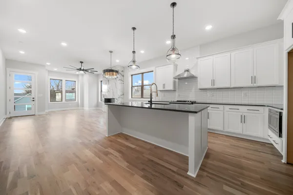 a large kitchen with stainless steel appliances granite countertop a large center island a oven a refrigerator and white cabinets