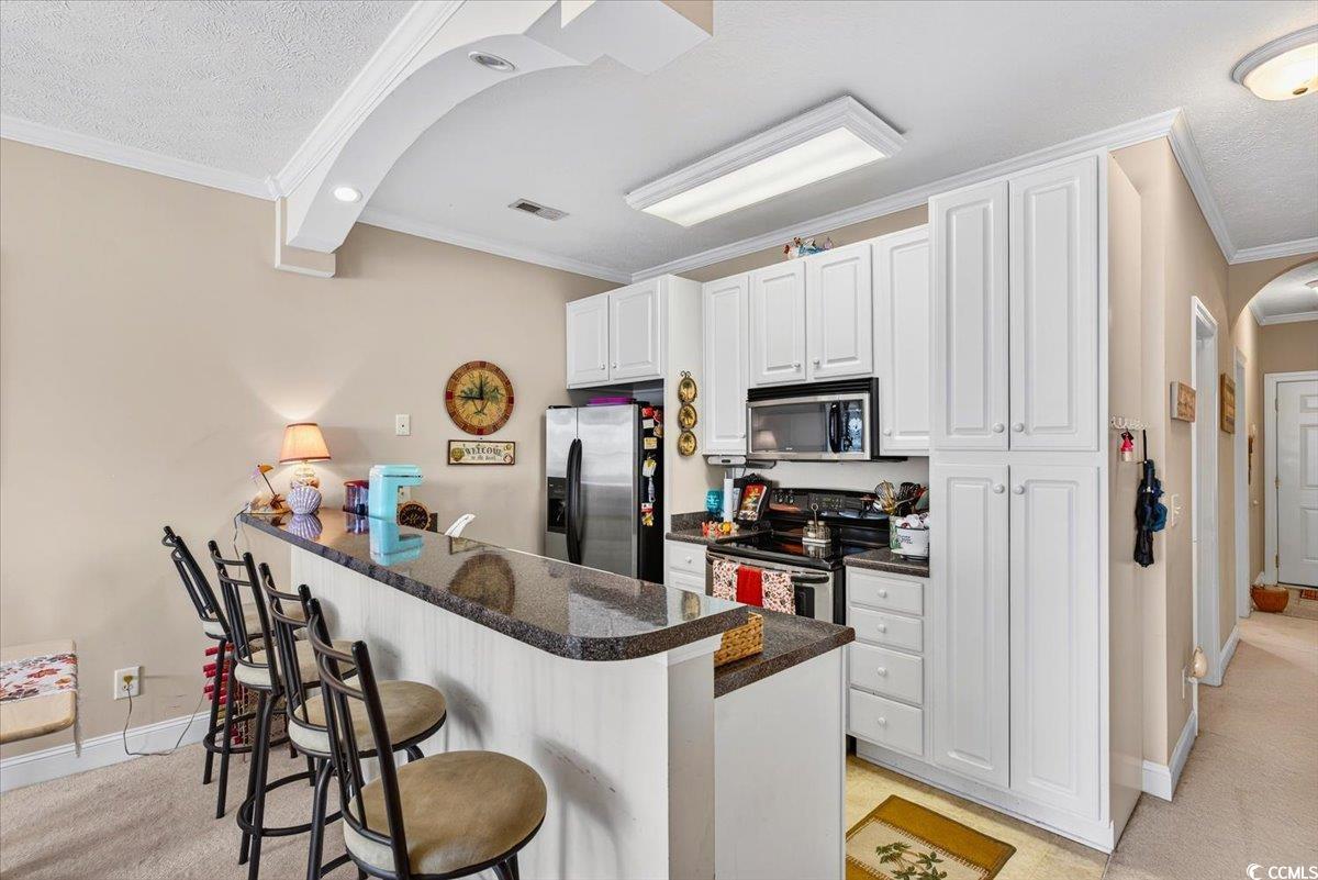 131 Waypoint Ridge Avenue, Unit 24 Little River, SC 29566 - Photo 18 of 39 Kitchen with arched walkways, a kitchen breakfast bar, white cabinets, appliances with stainless steel finishes, and a peninsula