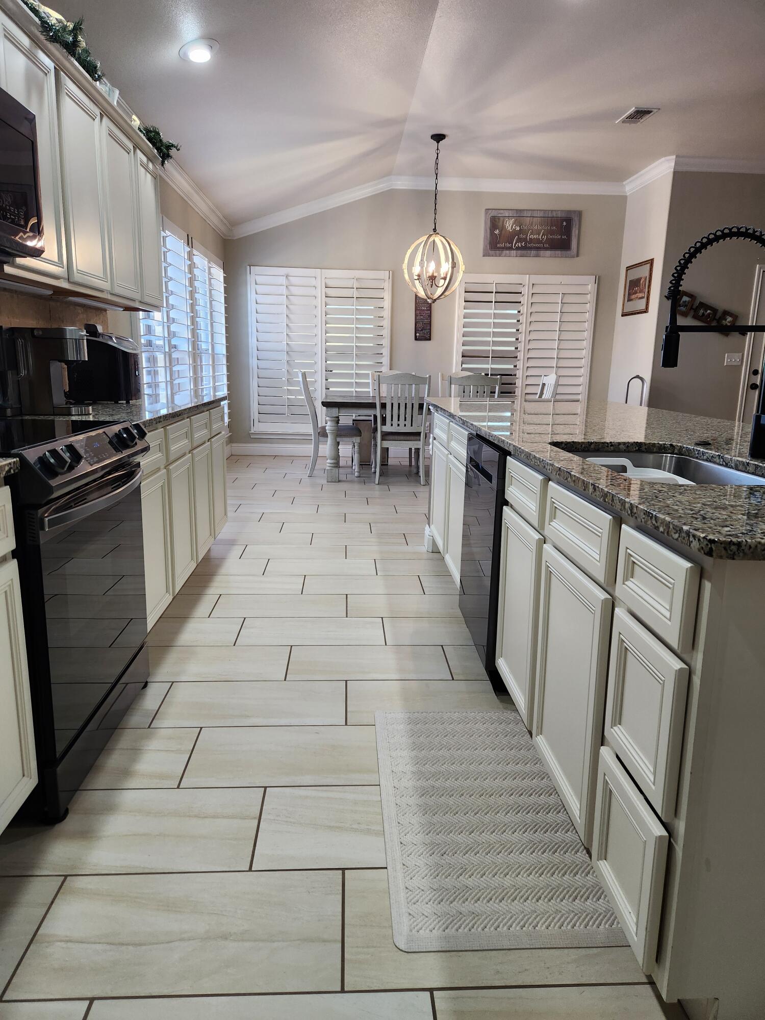 7217 91st Street Lubbock, TX 79424 - Photo 9 of 27 a large kitchen with stainless steel appliances granite countertop a stove a sink dishwasher and white cabinets with wooden floor