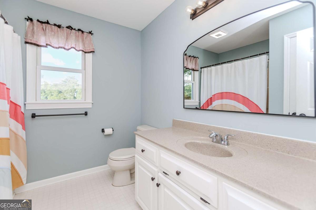 6441 Hog Mountain Road Bogart, GA 30622 - Photo 25 of 57 a bathroom with a granite countertop sink mirror vanity and toilet