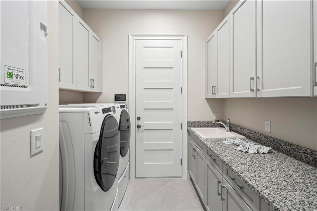 8795 Calypso Court Naples, FL 34113 - Photo 24 of 49 a utility room with cabinets washer and dryer