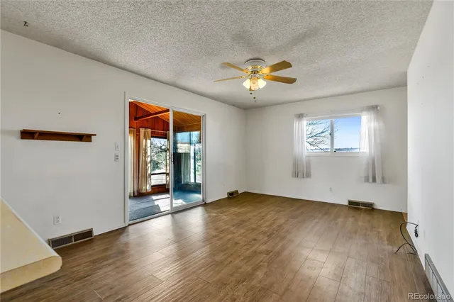 an empty room with wooden floor chandelier and windows