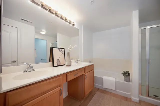 a bathroom with a double vanity sink mirror and bathtub