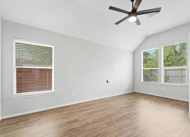 a view of empty room with wooden floor and fan