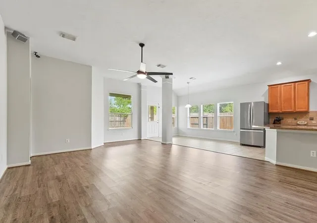 a view of an empty room with window and wooden floor