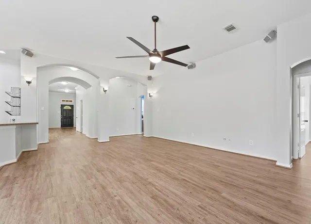 a view of a big room with wooden floor and a ceiling fan
