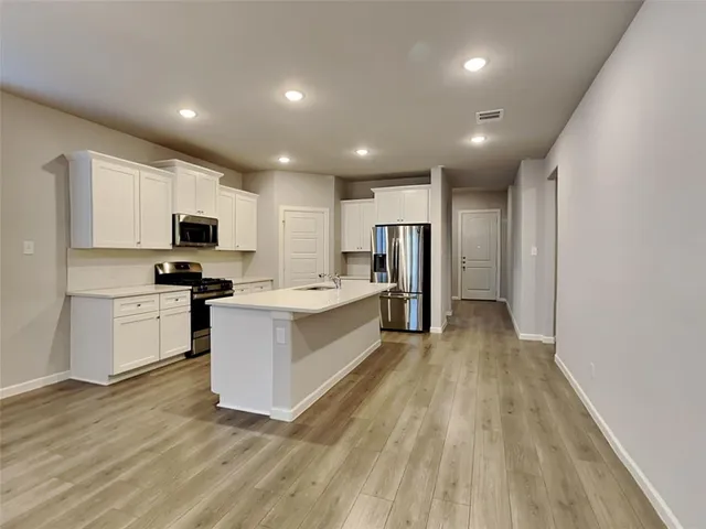 a large kitchen with kitchen island granite countertop a stove top oven a sink dishwasher and a refrigerator with wooden floor