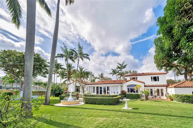 a front view of a house with a garden and lake view