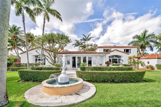 a front view of a house with a garden and trees