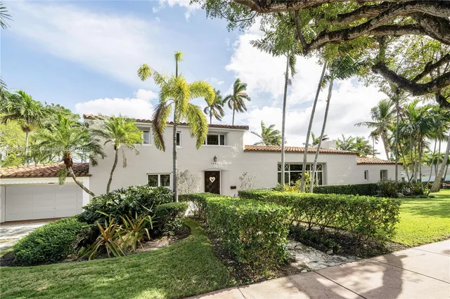 a front view of a house with a yard and potted plants