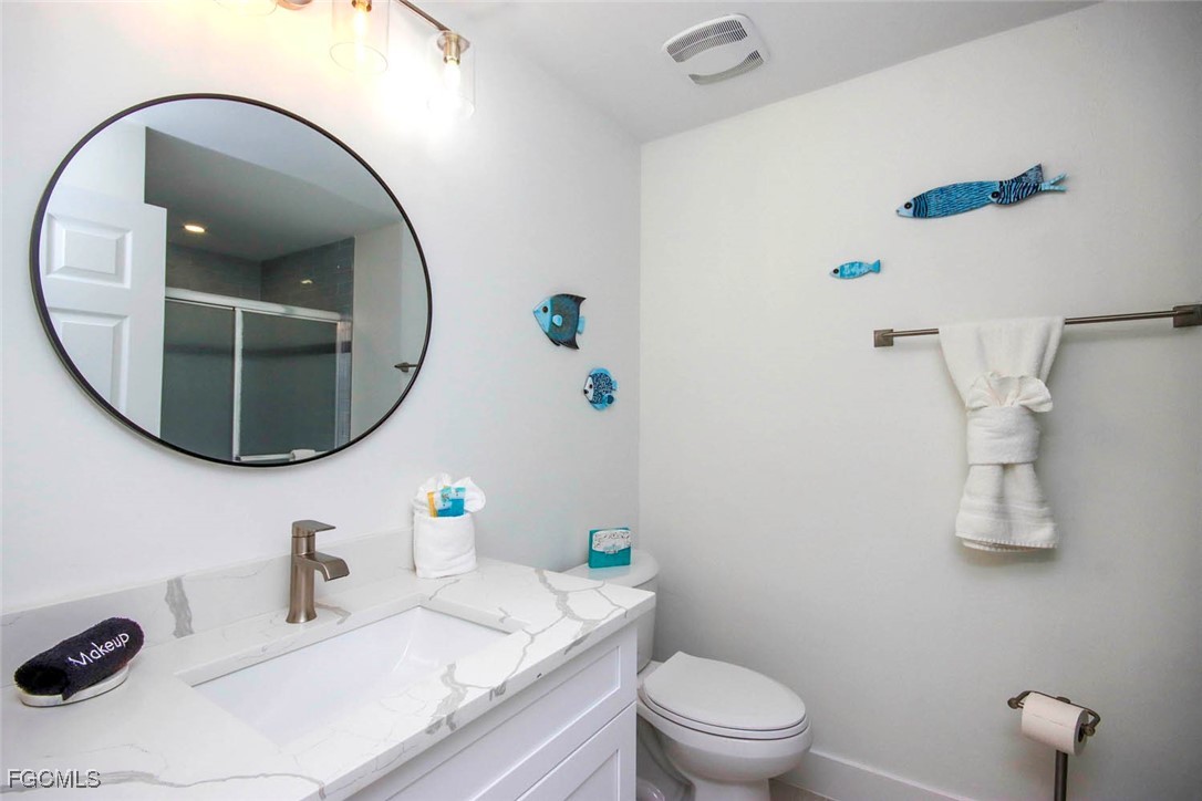 5117 Sea Bell Road, Unit E103 Sanibel, FL 33957 - Photo 23 of 24 a bathroom with a granite countertop sink mirror and toilet