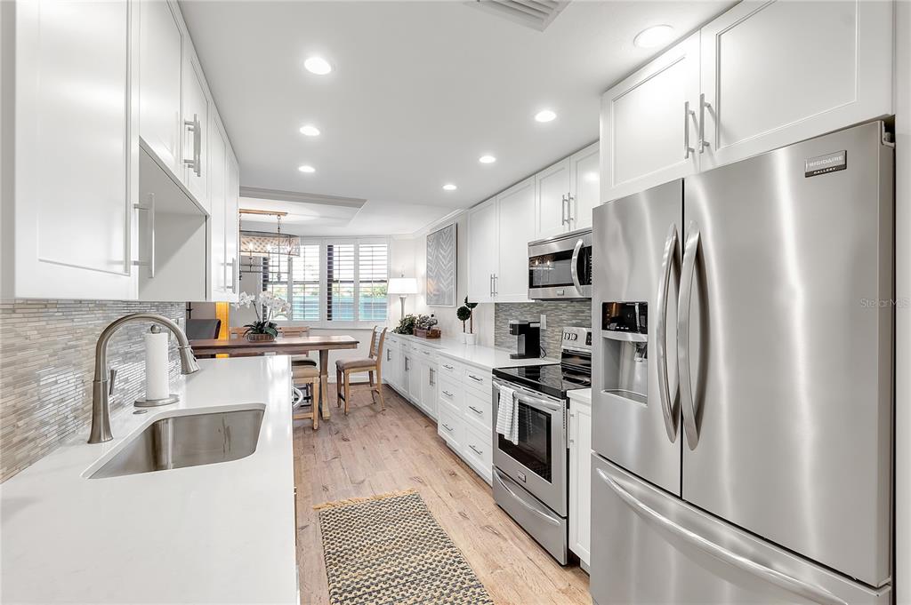 1000 Longboat Club Road, Unit 204 Longboat Key, FL 34228 - Photo 12 of 66 a kitchen with white cabinets and stainless steel appliances