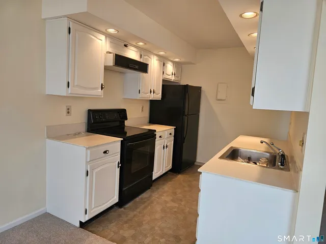 a kitchen with a refrigerator sink and cabinets