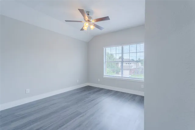 an empty room with wooden floor fan and windows