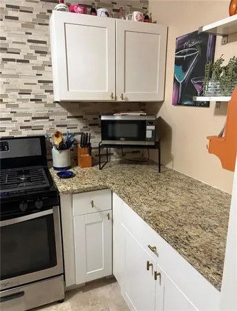 a kitchen with stainless steel appliances granite countertop a stove a sink and a microwave