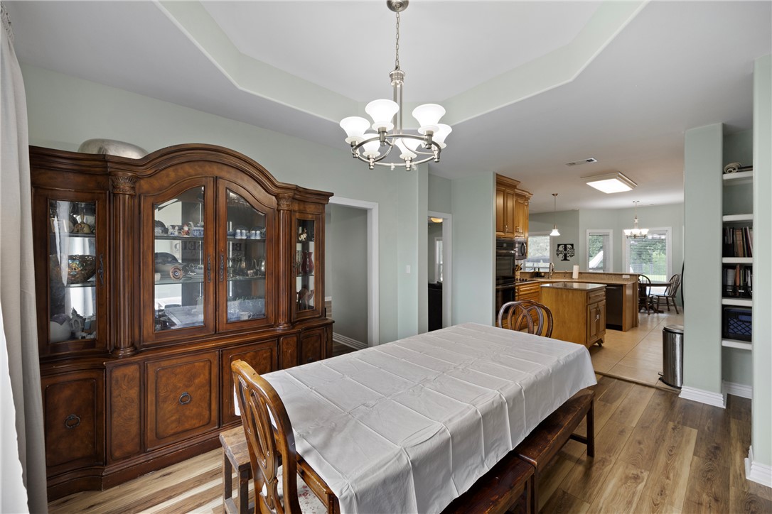 751 Walthall Road Russellville, AR 72802 - Photo 13 of 60 Dining area featuring wood-finish flooring and a tray ceiling with a chandelier