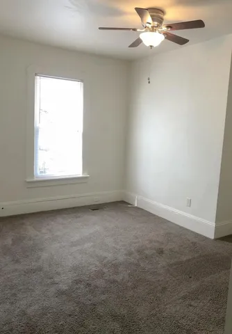 an empty room with a window and a fan