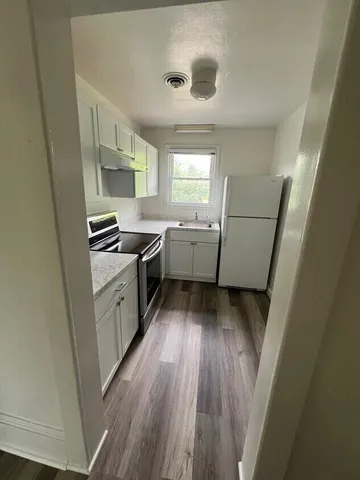 a kitchen with sink a refrigerator and wooden floor