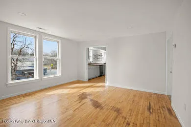 a view of an empty room with a window and wooden floor
