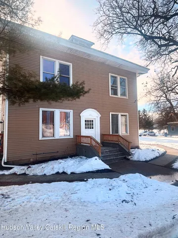 a front view of a house with a yard covered in snow