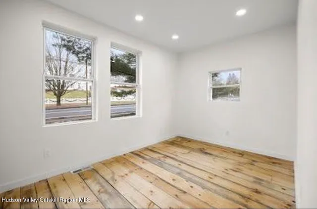 a view of a bedroom with wooden floor and window