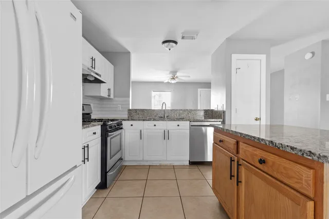 a kitchen with granite countertop white cabinets and white appliances