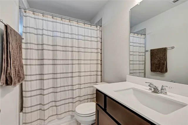 a bathroom with a sink a toilet and shower curtain