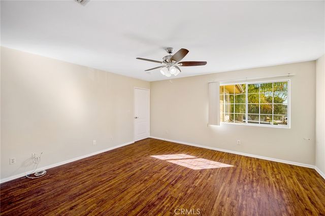 a view of a room with wooden floor and a ceiling fan
