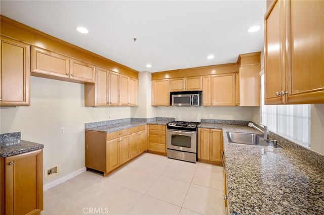 a large kitchen with stainless steel appliances granite countertop a stove a sink and a microwave