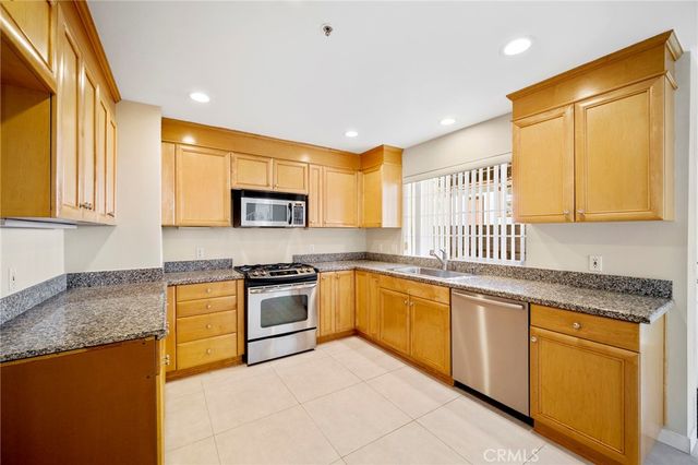 a kitchen with stainless steel appliances granite countertop a stove a sink and a microwave