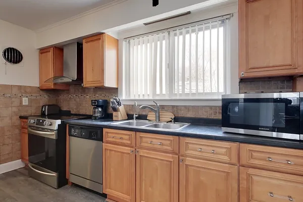 a kitchen with granite countertop white cabinets stainless steel appliances a sink and window