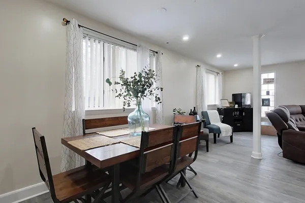 a living room with furniture a potted plant and open kitchen view