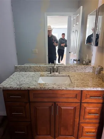 a bathroom with a granite countertop sink and a mirror