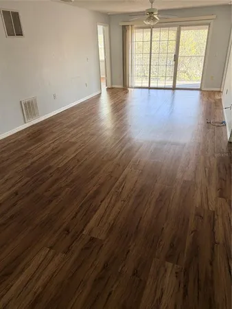 a view of an empty room with wooden floor and a window