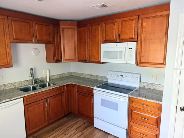 a kitchen with stainless steel appliances granite countertop wooden cabinets a sink and a stove