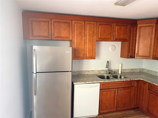 a kitchen with granite countertop stainless steel appliances a refrigerator a sink and cabinets